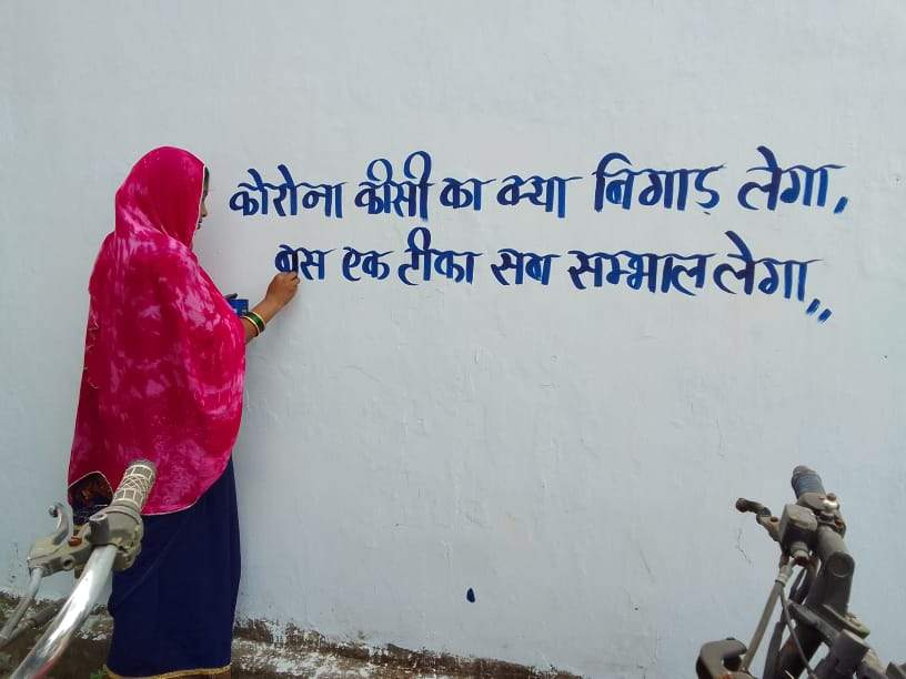 घर-घर तक दीवार लेखन से टीकाकरण का संदेश दे रहीं समूह की महिलाएं