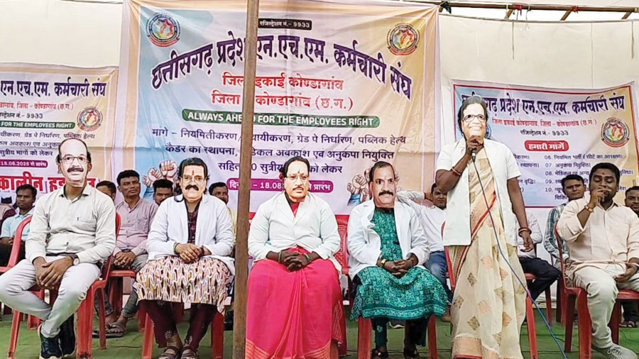 मुखौटा पहनकर एनएचएम कर्मियों का प्रदर्शन