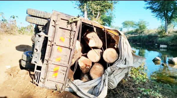 नदी किनारे लकड़ी से भरी वाहन पलटा