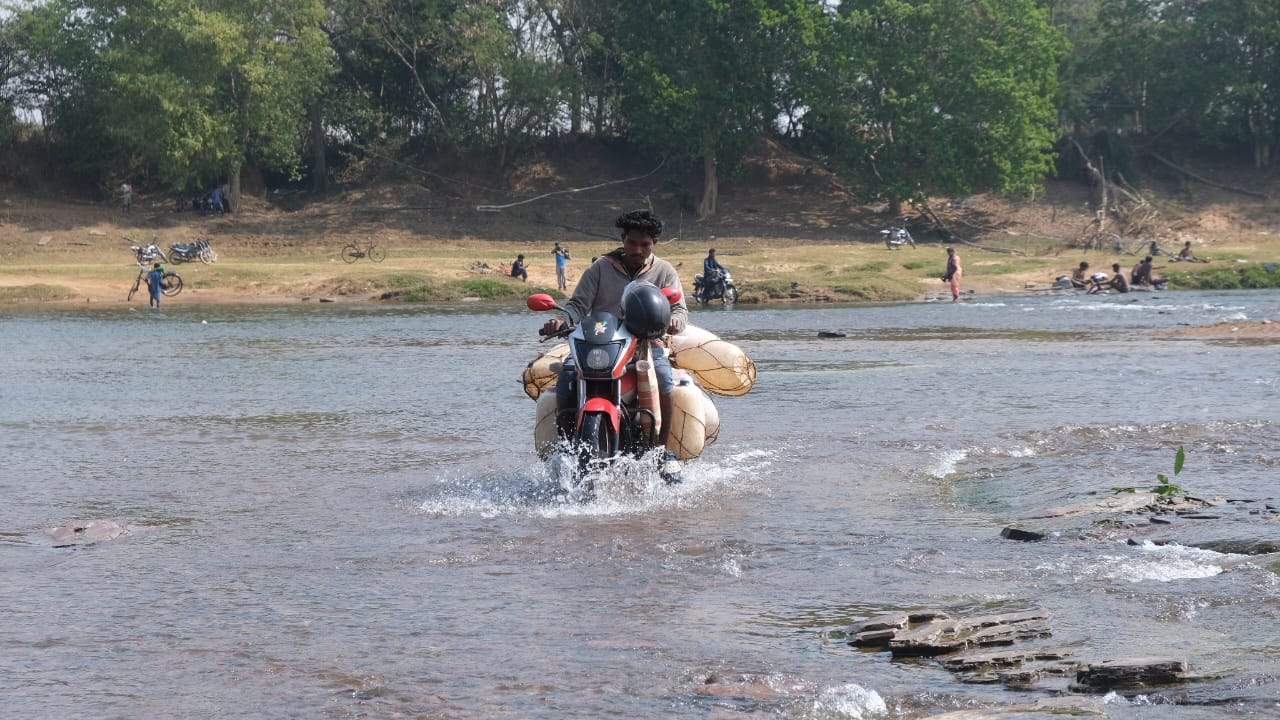 जगदलपुर से चित्रकोट जाने वाले रास्ते में करंजी के पास से इंद्रावती नदी गुजरती है। पानी का बहाव कम होने पर नदी के उस पार वाले गांव के लोग पैदल या मोटर सायकल से नदी पार कर शहर के लिए आते हैं। स्थानीय लोग यहांं छिंद का रस निकालकर उसे बड़े-बड़े प्लास्टिक के ब्लाडर में भरकर अपनी मोटर सायकल से बेचने शहर आते हैं। जो इनकी आमदनी का मुख्य स्रोत है। तस्वीर / ‘छत्तीसगढ़’ / विमल मिंज